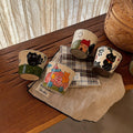 Hand-painted ceramic mugs with cute cat and house designs on wooden table