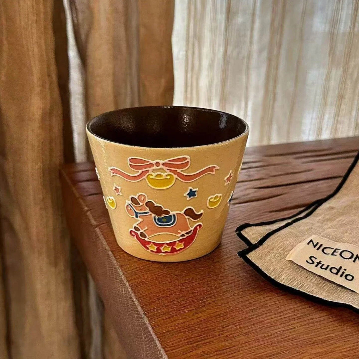 Handmade ceramic mug with festive reindeer design, perfect for coffee or tea, displayed on wooden shelf