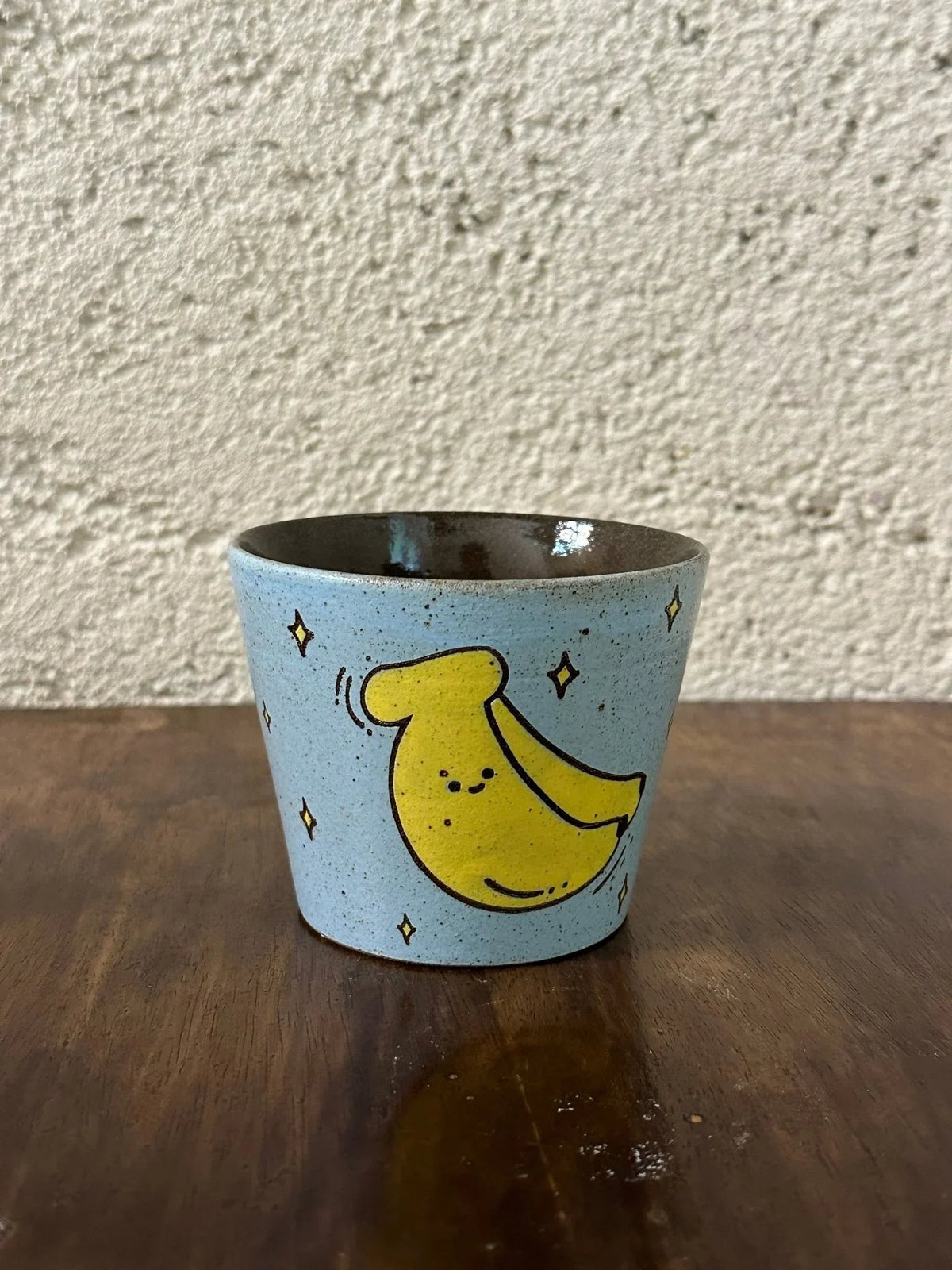 Handmade ceramic mug with cute yellow banana design, stars, light blue speckled glaze, perfect for coffee or tea