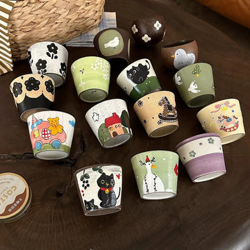 Hand-painted ceramic mugs with cute animal and floral designs, perfect for coffee or tea.