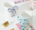 White ceramic mugs with iridescent bow handles, styled with cute accessories for tea or coffee