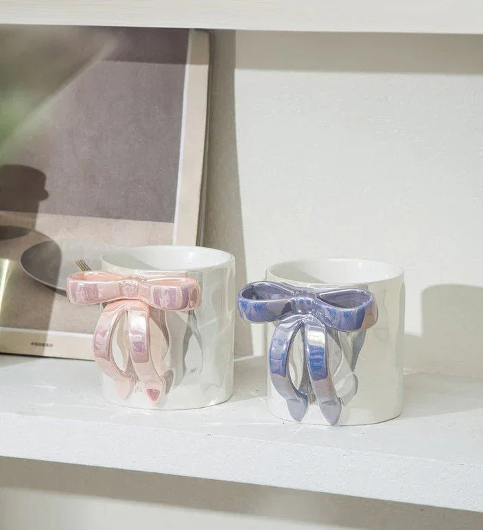 Handmade ceramic mugs with bow handles in pink and blue, perfect for coffee or tea