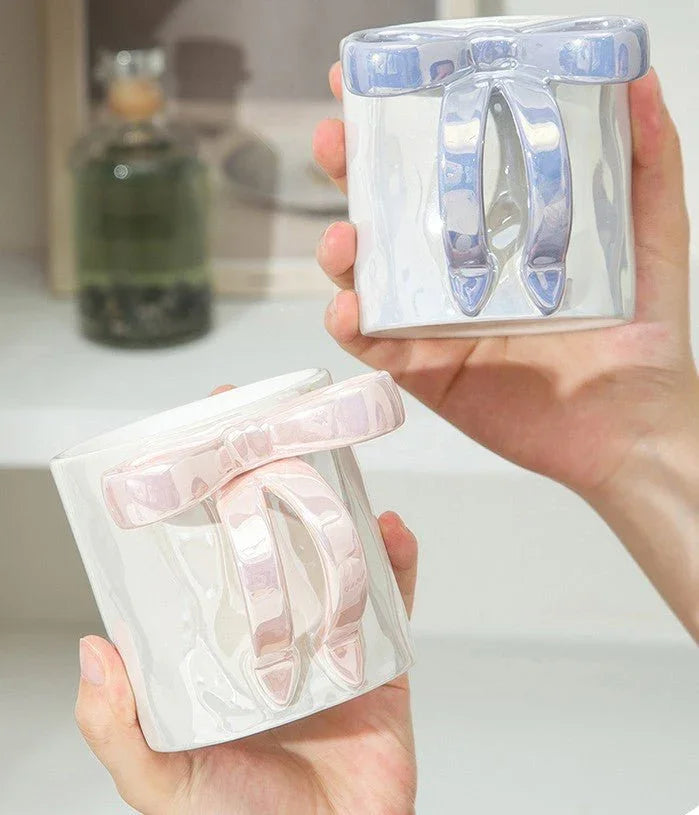 Handheld ceramic mugs with glossy bow handles, pink and blue, ideal for coffee or tea