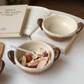 Handmade ceramic bowls with dried fruit, styled beside an open book for cozy tea moments.