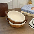 Handmade ceramic bowls with scalloped edges and handles, styled on wood table with cookbooks